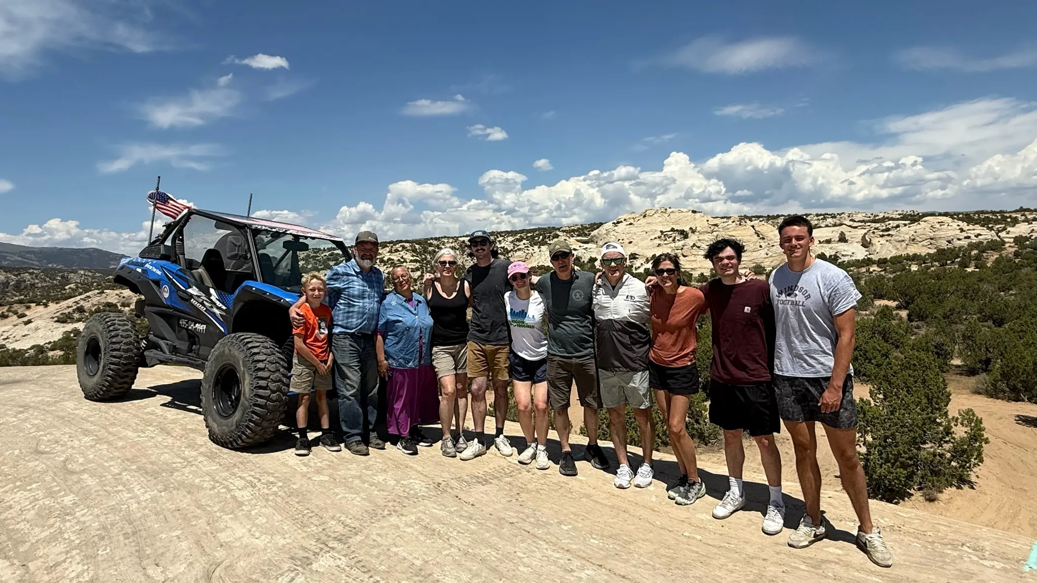 A multi-generational family group with their guided UTV on a slickrock overlook near Vernal, Utah